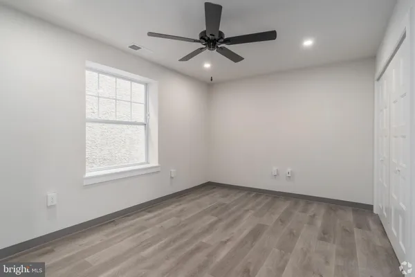 an empty room with a window and a ceiling fan
