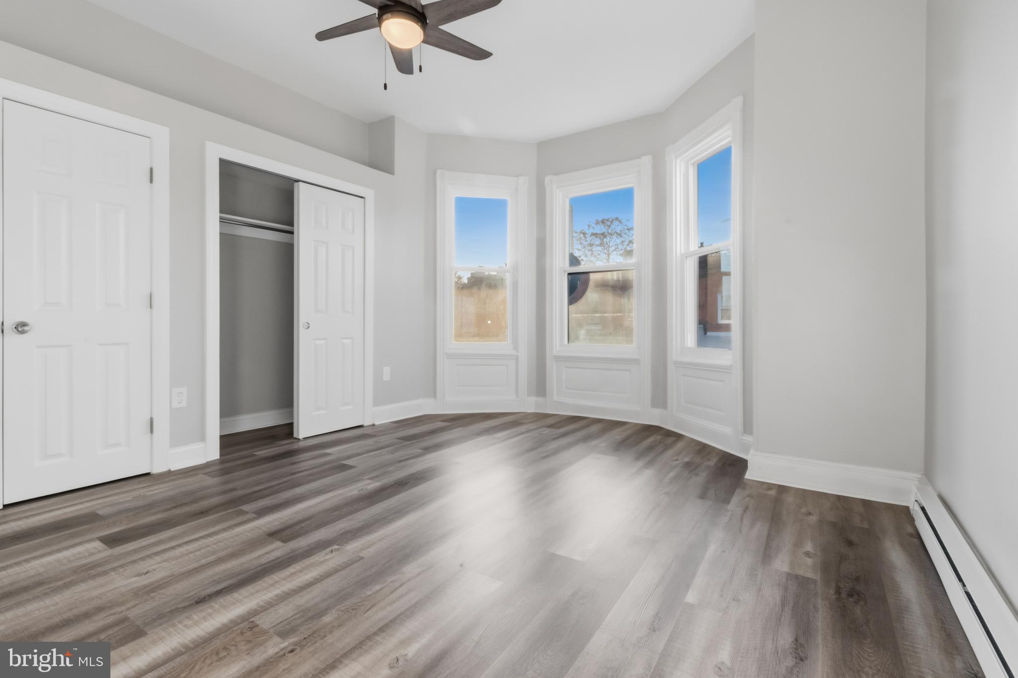 3545 North 11th Street, Unit 2F Philadelphia, PA 19140 - Photo 4 of 10 an empty room with wooden floor ceiling fan and windows