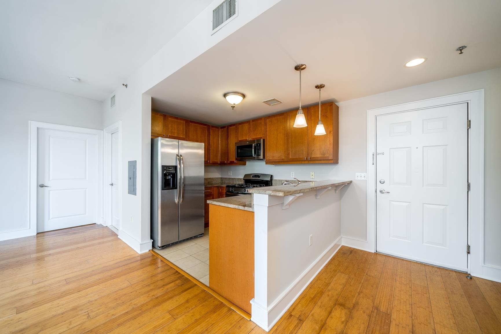 924 Jefferson Street, Unit 2A Hoboken, NJ 07030 - Photo 5 of 20 a kitchen with stainless steel appliances granite countertop a refrigerator a sink dishwasher a stove and white countertops with wooden floor