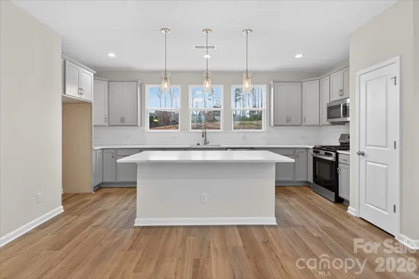a view with kitchen island wooden floors and stainless steel appliances