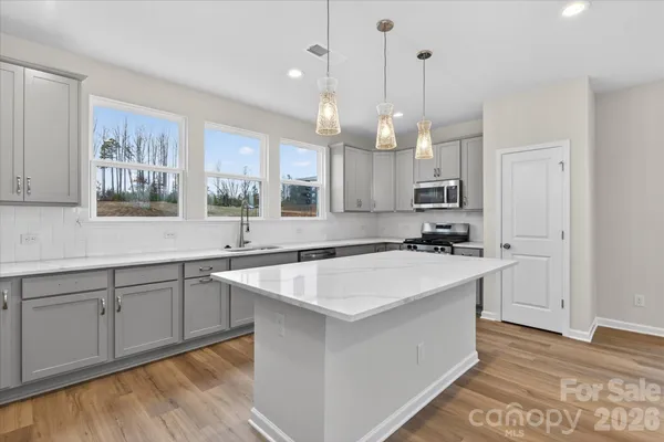 a kitchen with kitchen island a sink a stove a center island and a window