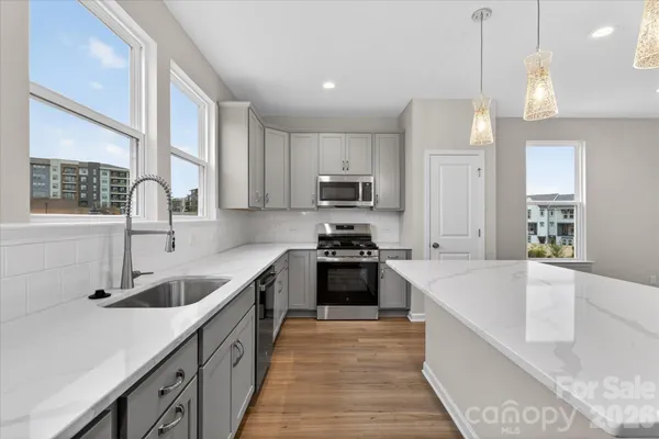 a kitchen with stainless steel appliances granite countertop a sink a stove and a wooden floors