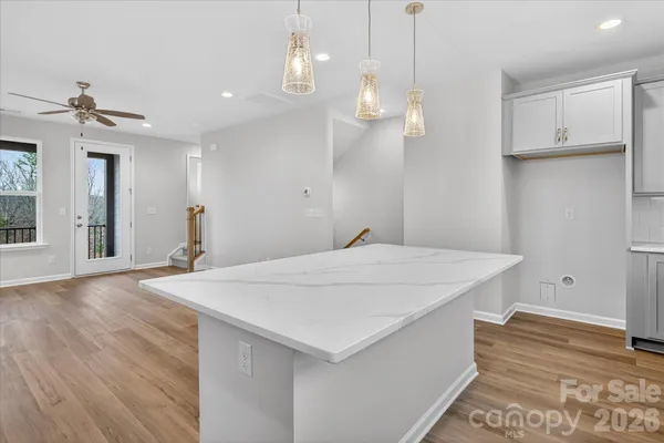 a room with kitchen island stainless steel appliances sink and wooden floor