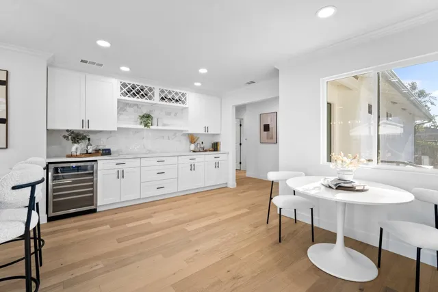 a kitchen with stainless steel appliances kitchen island granite countertop a stove a sink a dining table and chairs with wooden floor