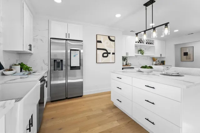 a kitchen with stainless steel appliances kitchen island granite countertop a refrigerator and a sink