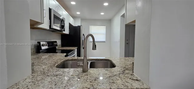 a kitchen with stainless steel appliances granite countertop a sink a refrigerator and a granite counter tops