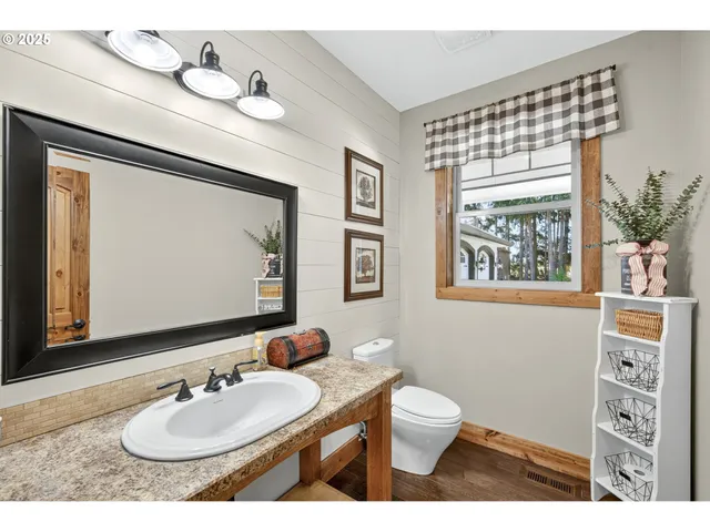 a bathroom with a toilet a sink a mirror and a window