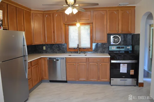 a kitchen with stainless steel appliances granite countertop a refrigerator a stove and a sink