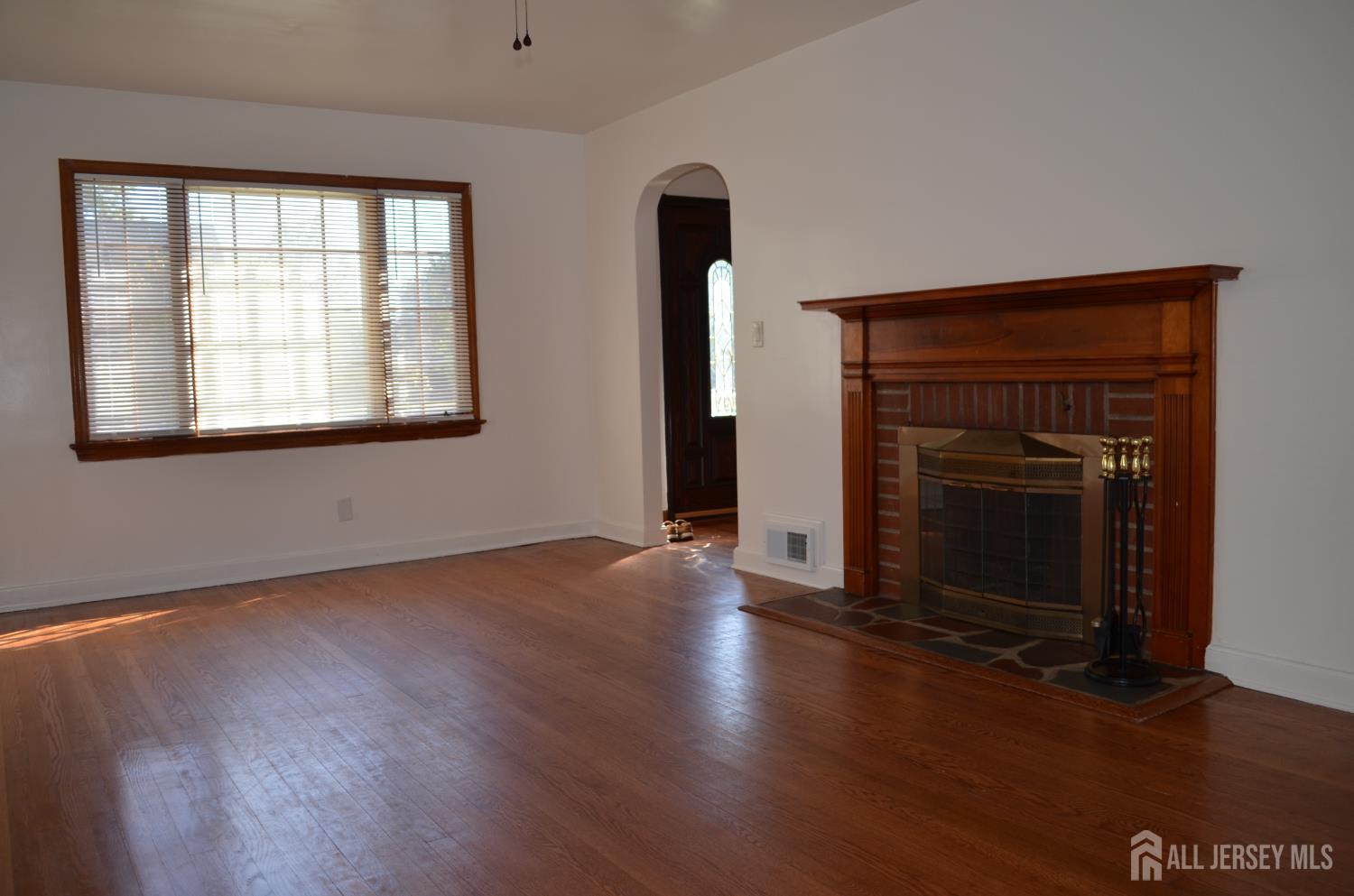 550 4th Street Dunellen, NJ 08812 - Photo 27 of 30 an empty room with wooden floor fireplace and windows