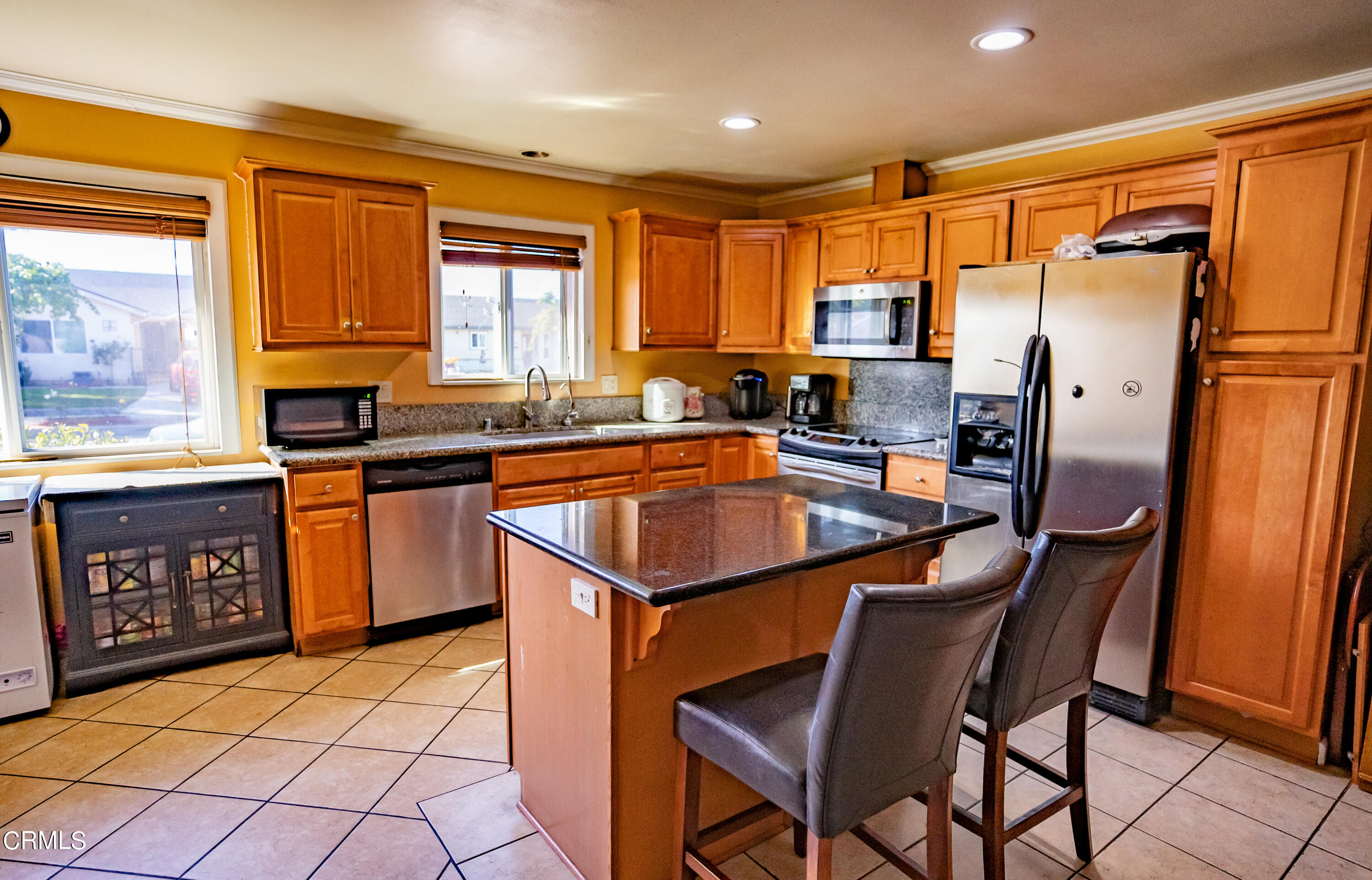 a kitchen with stainless steel appliances granite countertop a sink a stove a refrigerator cabinets and a dining table