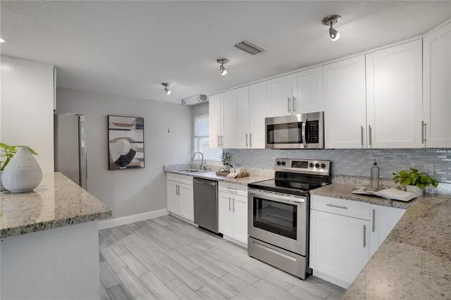 a kitchen with stainless steel appliances granite countertop a stove a sink and a microwave