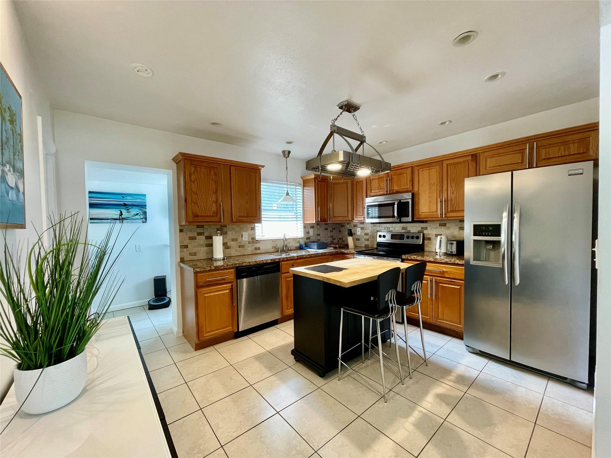 29 Northeast 3rd Street, Unit B Dania Beach, FL 33004 - Photo 3 of 18 a kitchen with stainless steel appliances granite countertop a refrigerator a sink a stove a dining table and chairs