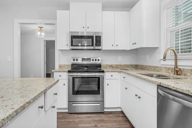 a kitchen with granite countertop white cabinets stainless steel appliances and a sink