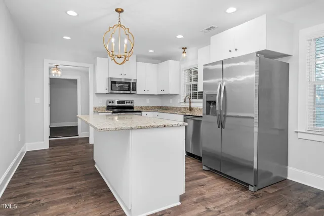 a kitchen with stainless steel appliances granite countertop a refrigerator a stove and a sink