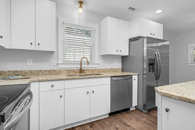 a kitchen with granite countertop cabinets stainless steel appliances a sink and wooden floor