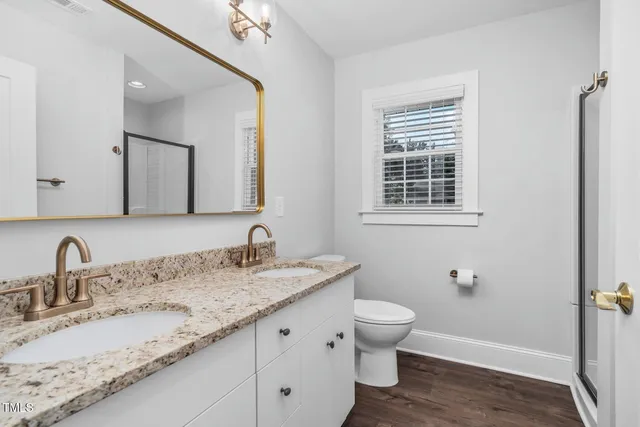 a bathroom with a granite countertop sink toilet and mirror