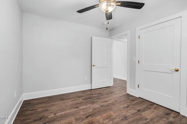 an empty room with wooden floor fan and window