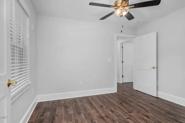 a view of an empty room with a window and wooden floor