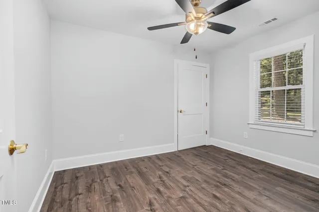 an empty room with a window and a ceiling fan