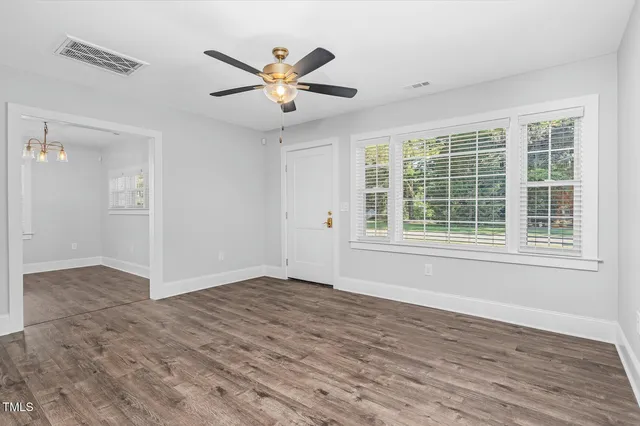 a view of an empty room with wooden floor and a window