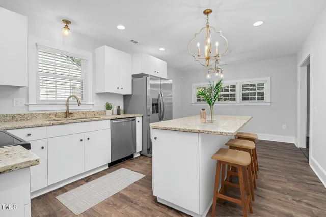 a kitchen that has a lot of white cabinets and wooden floor