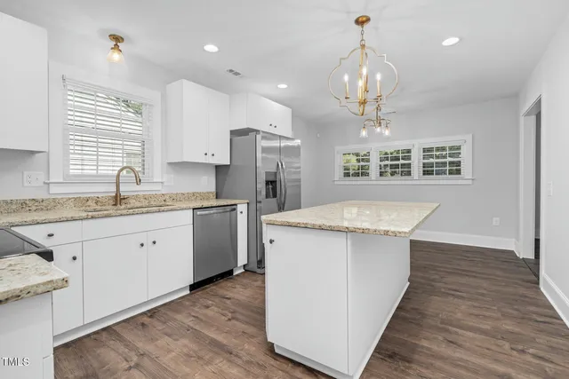 a kitchen with kitchen island granite countertop a sink refrigerator and cabinets