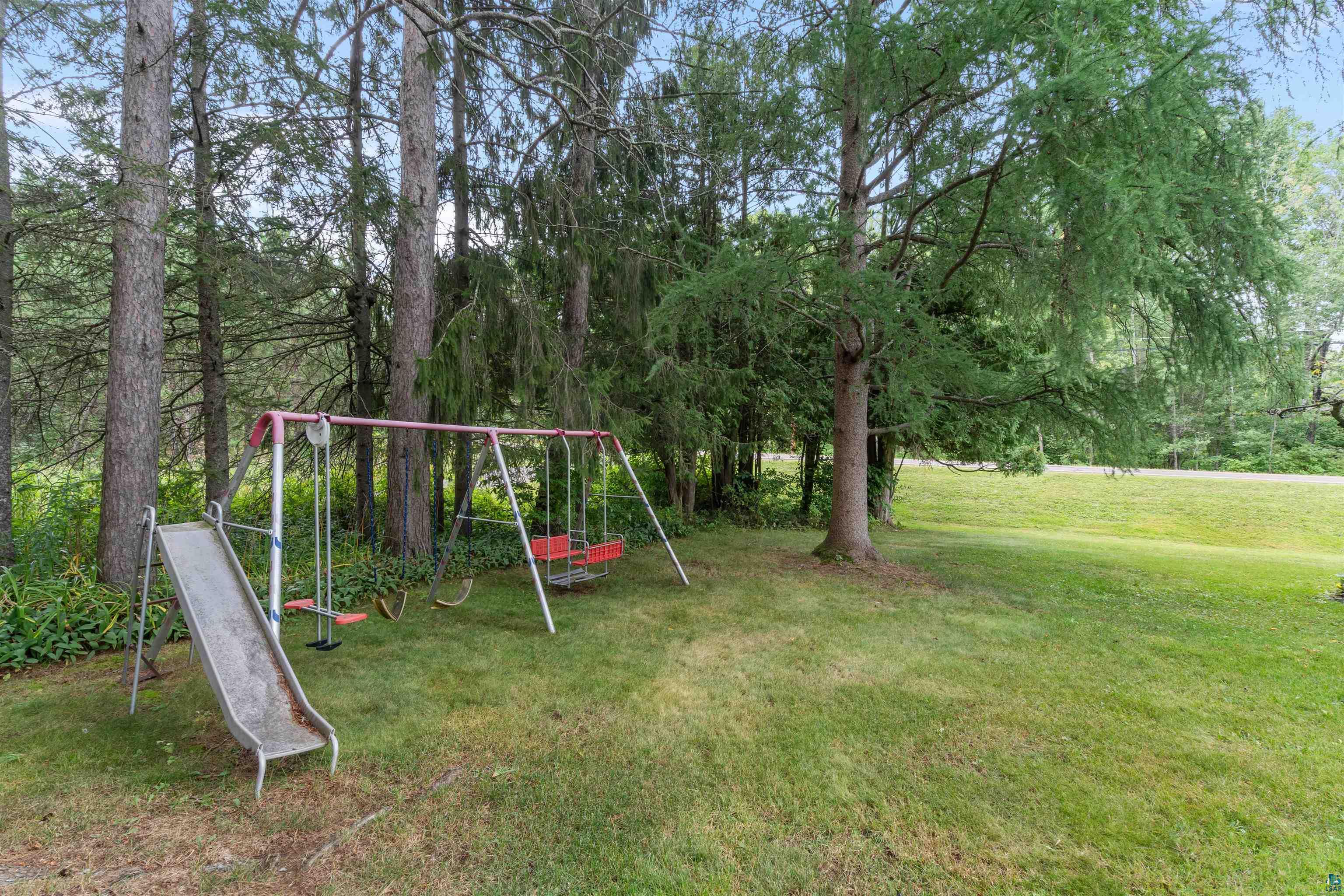 4793 Anderson Road Hermantown, MN 55811 - Photo 33 of 39 Expansive grassy area featuring mature trees and a metal swing set with a slide