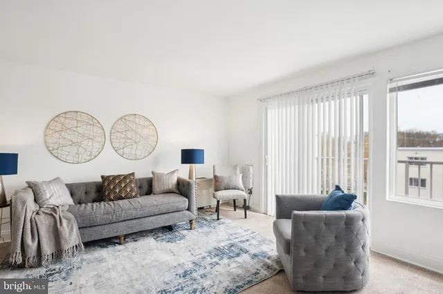 a living room with furniture a large window and a potted plant