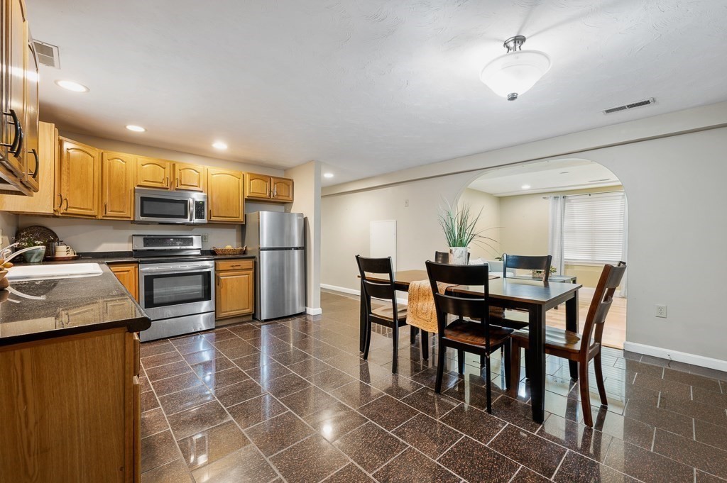 1 Hatfield Street, Unit 3 Worcester, MA 01604 - Photo 9 of 23 a kitchen with stainless steel appliances kitchen island granite countertop a table chairs and a refrigerator