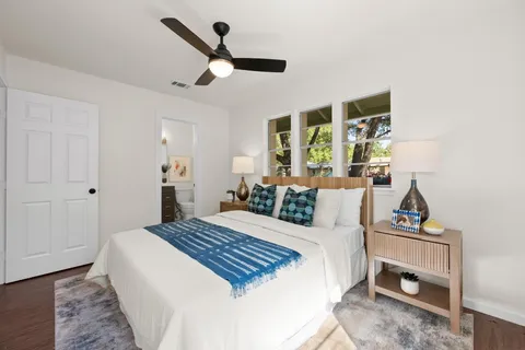 a bedroom with a bed a large window and a potted plant