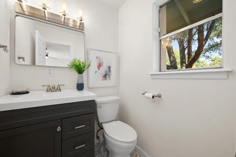 a bathroom with a granite countertop sink mirror and toilet