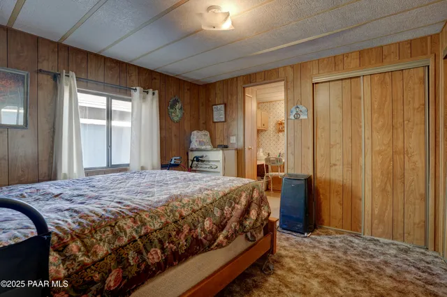 a bedroom with a bed table and a large window