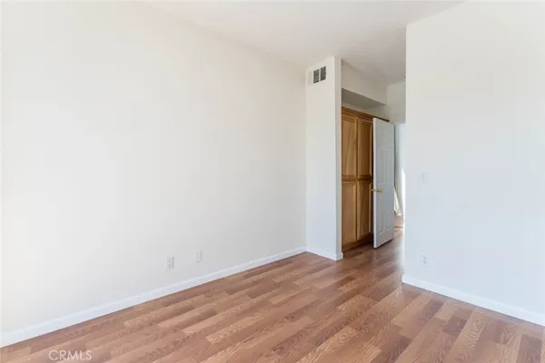 a view of an empty room with wooden floor and closet