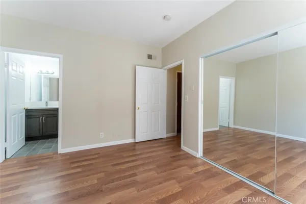 a view of an empty room with wooden floor and a bathroom