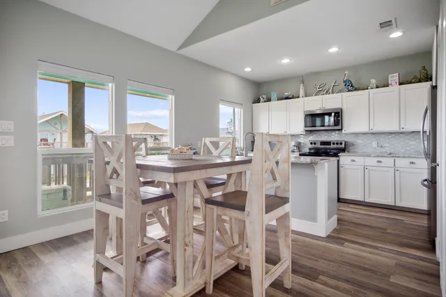 a kitchen with stainless steel appliances granite countertop a sink a stove and white cabinets