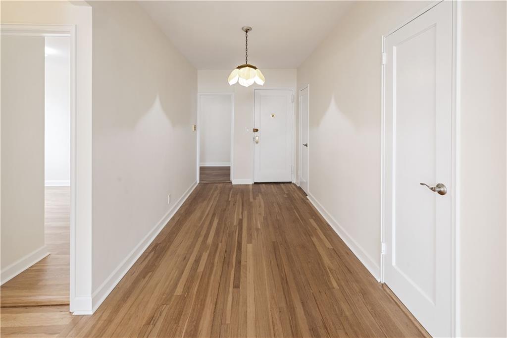 6801 Shore Road, Unit 4J Brooklyn, NY 11220 - Photo 3 of 15 a view of a hallway with wooden floor and a chandelier