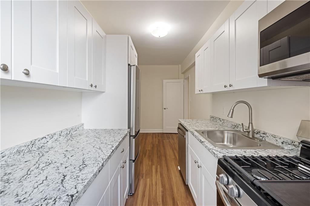 6801 Shore Road, Unit 4J Brooklyn, NY 11220 - Photo 5 of 15 a kitchen with stainless steel appliances granite countertop a sink stove and cabinets