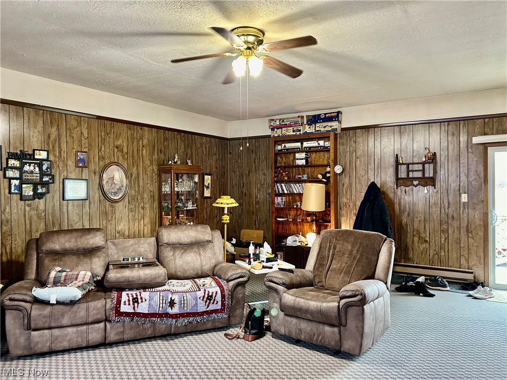 4030 Canton Road Northwest Carrollton, OH 44615 - Photo 6 of 34 Living room featuring a textured ceiling, baseboard heating, ceiling fan, carpet, and wood walls