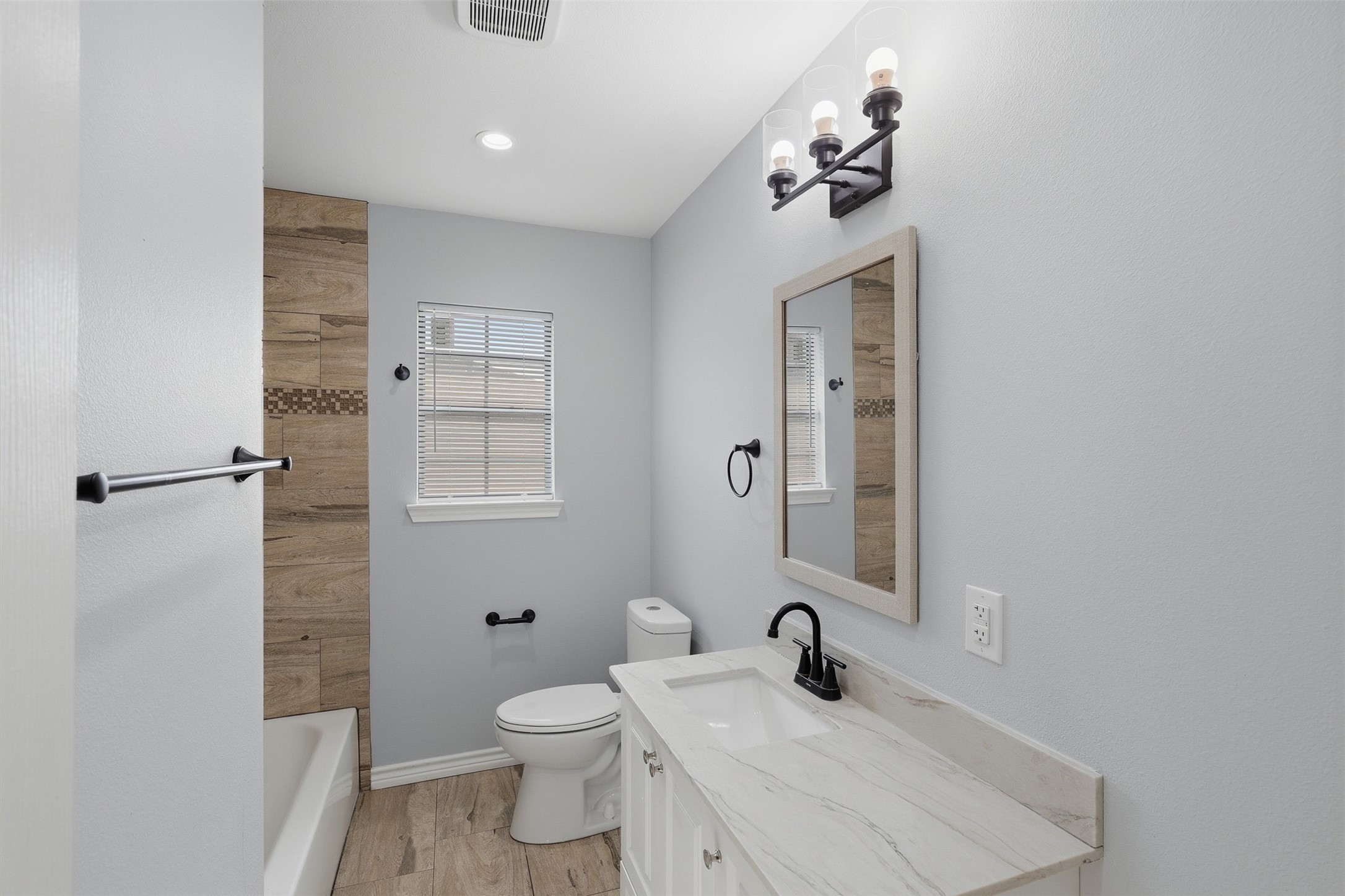 4926 Edfield Street Houston, TX 77033 - Photo 11 of 30 Bright, modern bathroom featuring a stylish vanity with a sleek marble countertop, elegant lighting, and a beautifully tiled shower area.