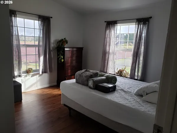 a bedroom with a bed window and wooden floor