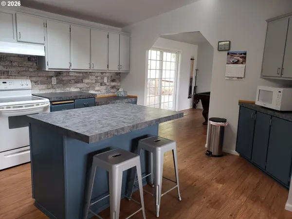 a kitchen with granite countertop a stove a sink dishwasher and cabinets with wooden floor