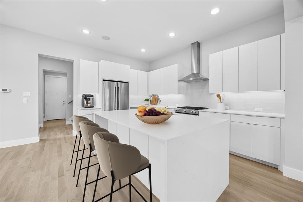 a kitchen with stainless steel appliances granite countertop a sink a stove a refrigerator and white cabinets with wooden floor