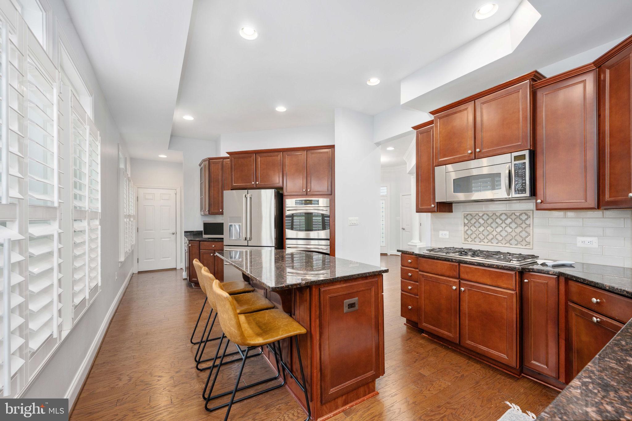 6044 Masondale Road Alexandria, VA 22315 - Photo 20 of 64 a kitchen with stainless steel appliances granite countertop wooden cabinets a sink dishwasher a stove and a refrigerator with wooden floor
