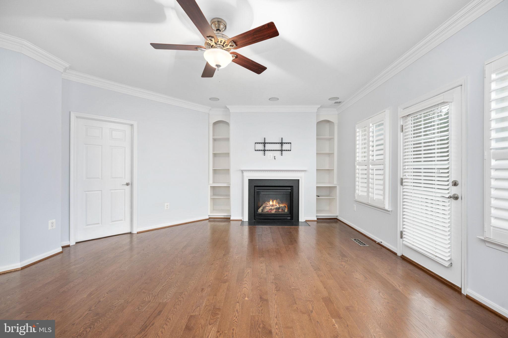 6044 Masondale Road Alexandria, VA 22315 - Photo 31 of 64 an empty room with windows a fireplace a ceiling fan and wooden floor