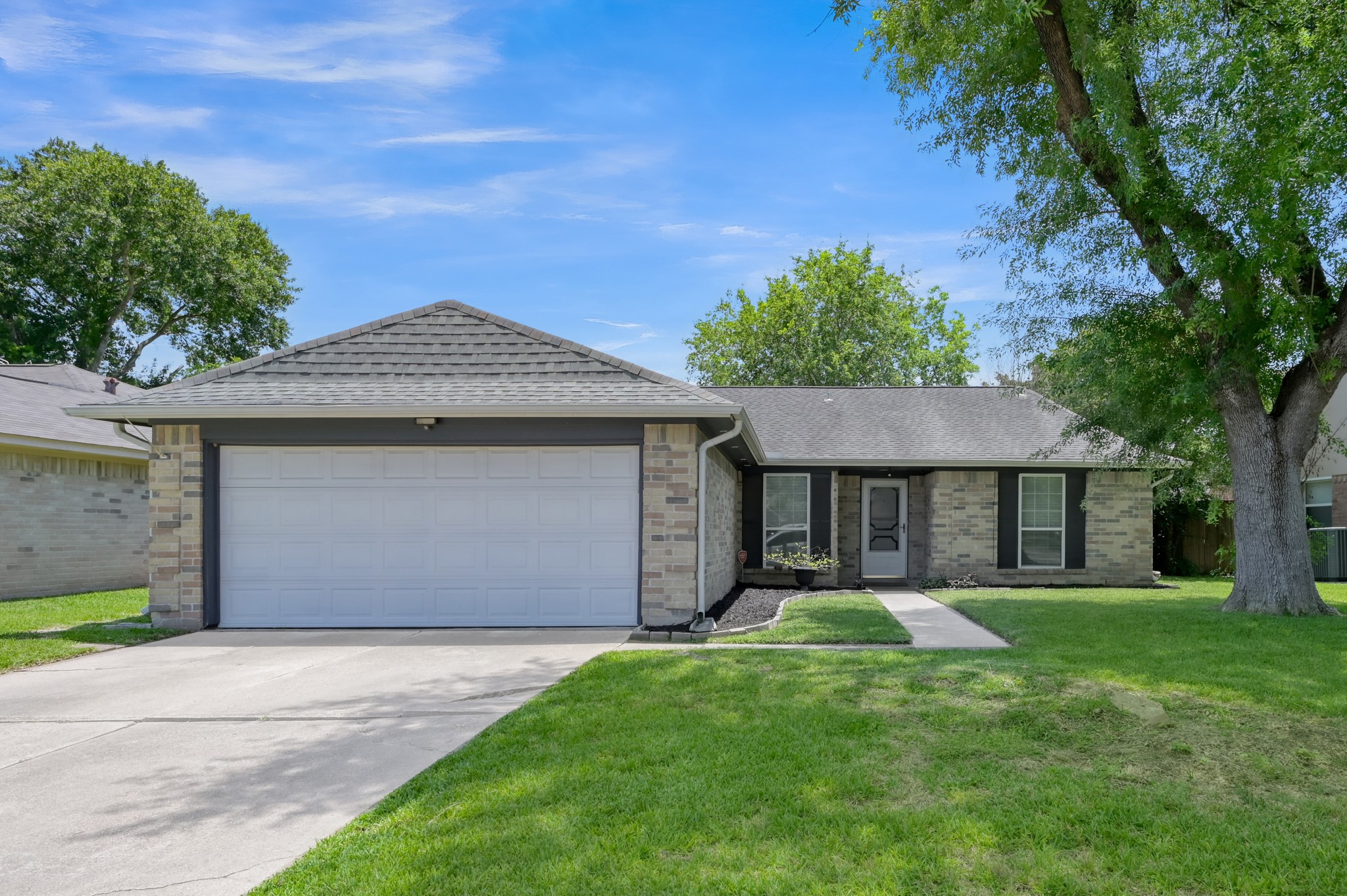 12015 Fallbrook Drive Houston, TX 77065 - Photo 1 of 29 This photo shows a charming single-story brick home with a two-car garage, a neatly maintained front lawn, and mature trees, offering great curb appeal.