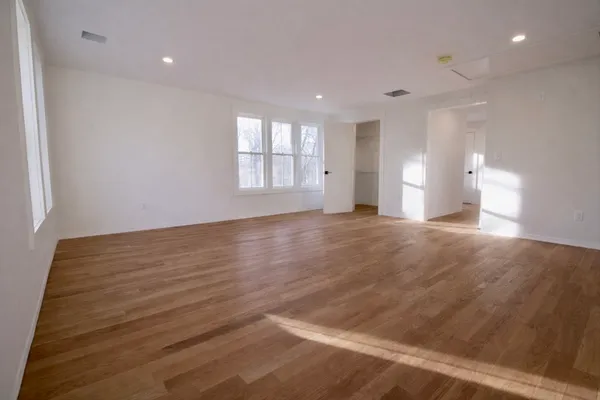 a view of empty room with wooden floor and window