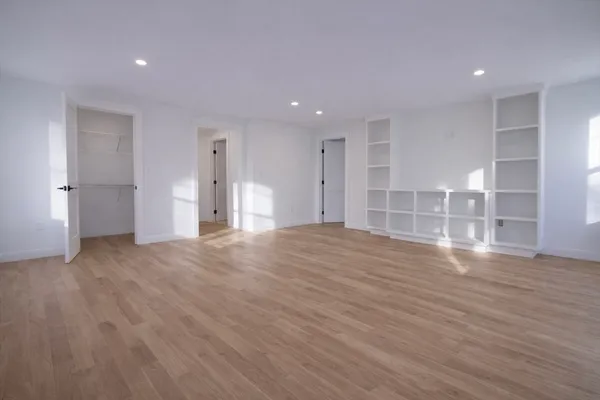 a view of empty room with wooden floor and window