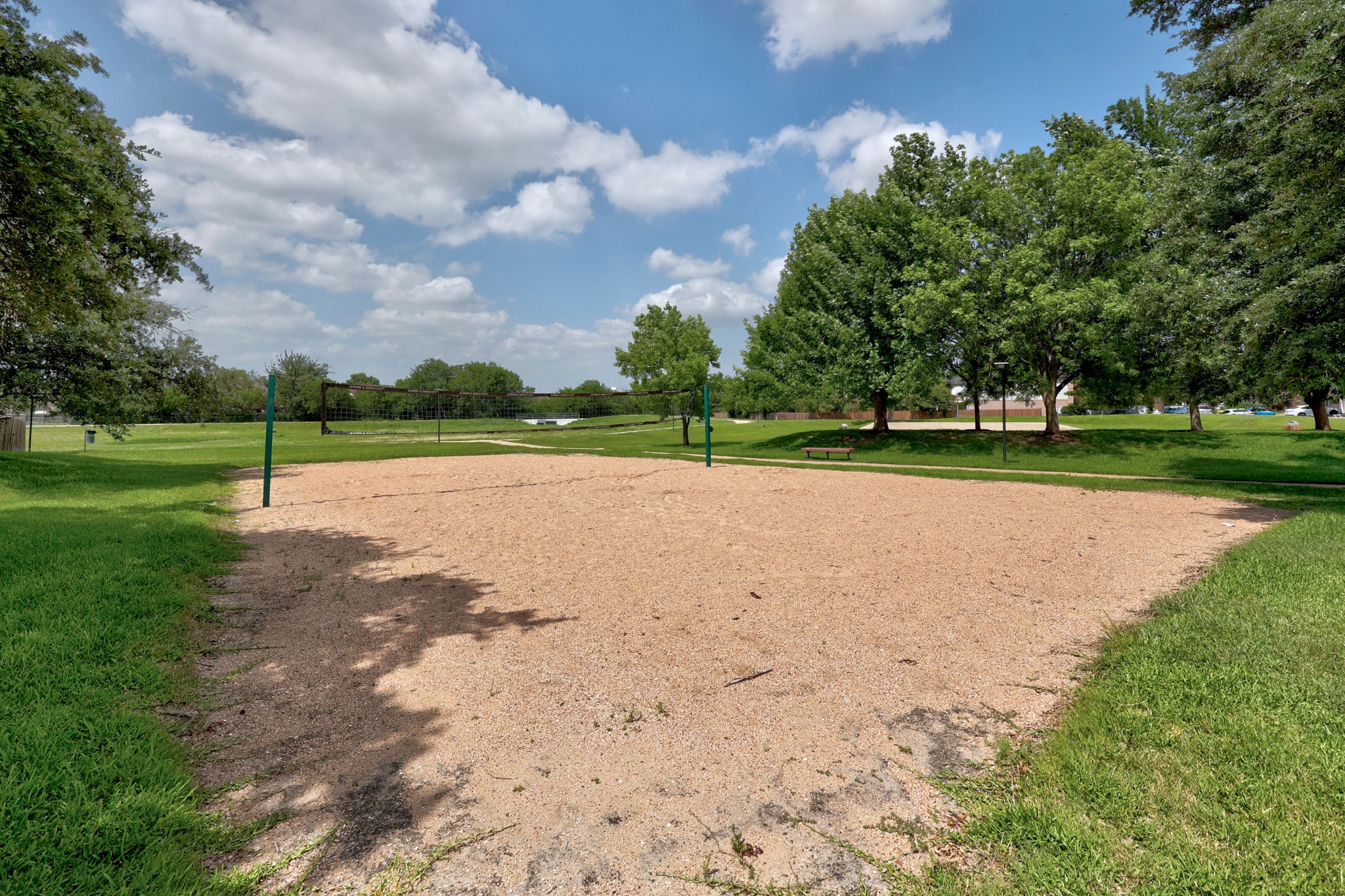 1108 Springbrook Road Pflugerville, TX 78660 - Photo 33 of 37 An inviting sand volleyball court awaits, nestled among vibrant green lawns and mature shade trees.