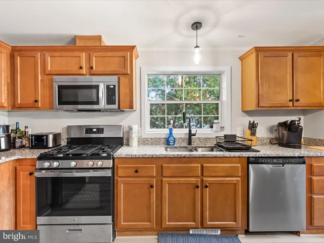 a kitchen with granite countertop a stove top oven microwave and cabinets