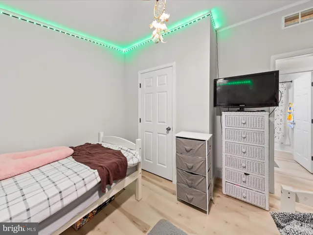 a bedroom with a bed and a flat tv screen on dresser